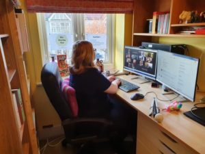 Amy sat in her home office space with 2 screens in front of her